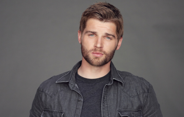 Молодой мужчина, американский актер Майкл Фогель на сером фоне