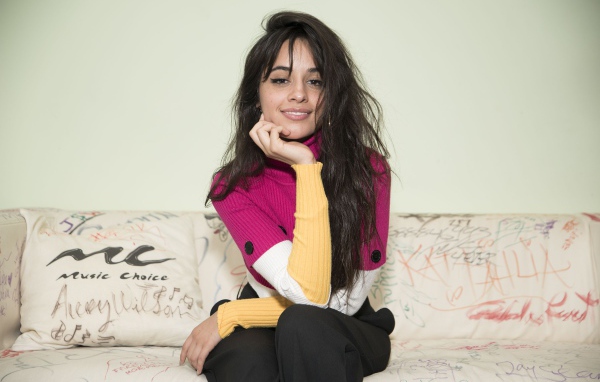 Улыбающаяся Камила Кабельо сидит на диване