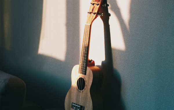 Желтая гитара стоит у серой стены