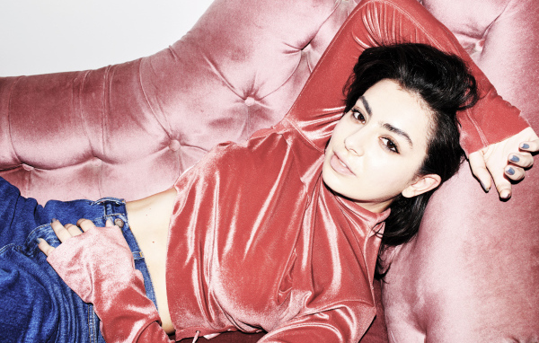 Молодая девушка Charli XCX лежит на диване