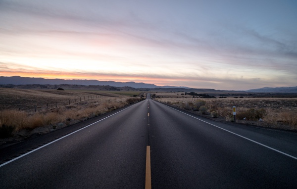 Асфальтная дорога уходит вдаль на фоне неба