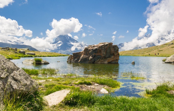Большой камень в воде на фоне голубого неба