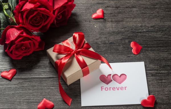 Букет красных роз с подарком и открыткой на столе