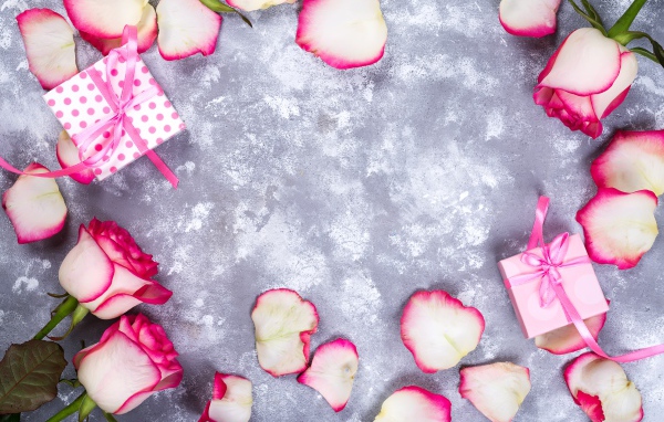Красивые розовые розы с лепестками и подарками на сером фоне