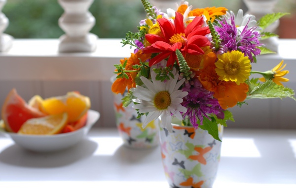 Букет разноцветных  садовых цветов в вазе на столе 