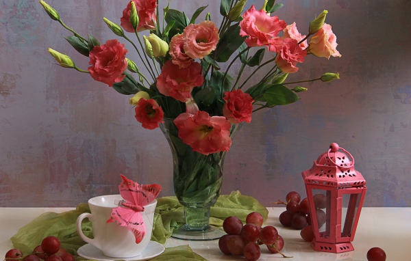 Букет розовых цветов эустомы на столе с виноградом