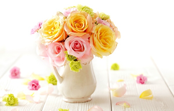 Желтые и розовые розы в вазе на столе 