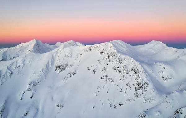 Красивые заснеженные вершины горы на фоне розового неба