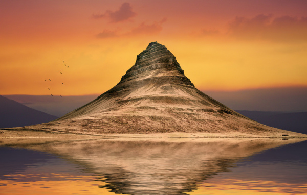 Mountain reflected in the water against the sky at sunset