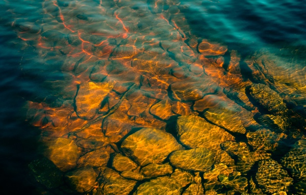 Камни на дне озера с чистой водой в лучах солнца