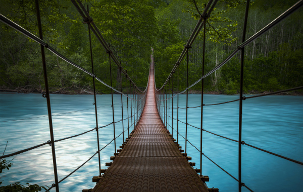 Suspension bridge over fast blue water river