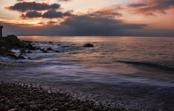 Мелкие камни на берегу моря на закате