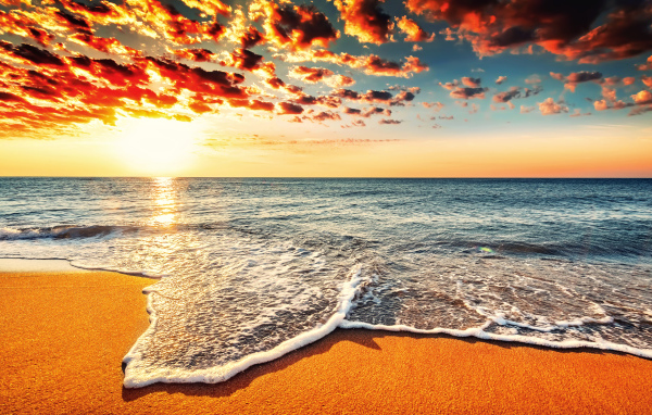 Белая морская пена на оранжевом песке под красивым небом