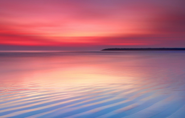 Мокрый белый песок на берегу океана на закате