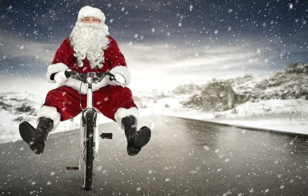 Санта Клаус на велосипеде на скользкой дороге зимой