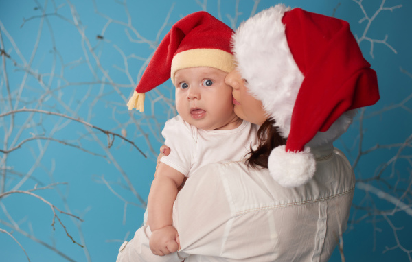 Маленький ребенок в новогоднем костюме на руках у мамы