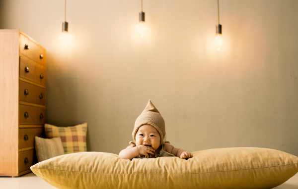Маленький ребенок лежит на подушке под лампами