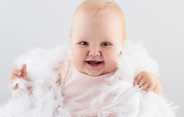 Смеющаяся маленькая девочка с перьями