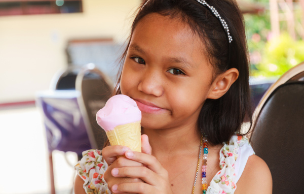 Маленькая девочка азиатка с мороженым в руке