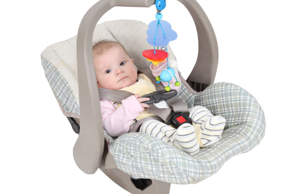 Маленький грудной ребенок в автомобильном кресле на белом фоне