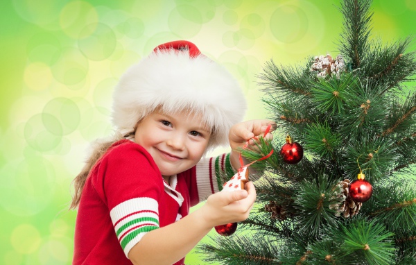 Little beautiful girl decorates a Christmas tree for the New Year.