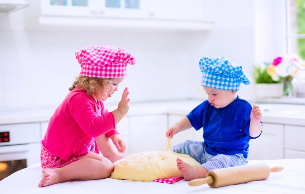 Маленькие мальчик и девочка на кухне с тестом