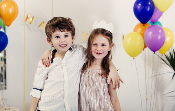 Маленькие мальчик и девочка на празднике с воздушными шарами