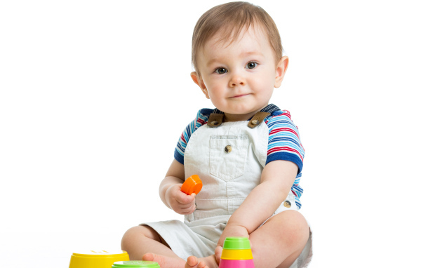 Маленький мальчик играет с пирамидкой на белом фоне