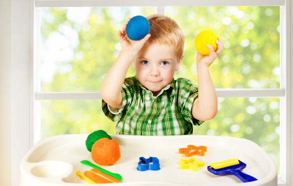 Маленький мальчик играет с игрушками у окна