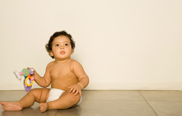 Маленький мальчик сидит на полу с игрушкой