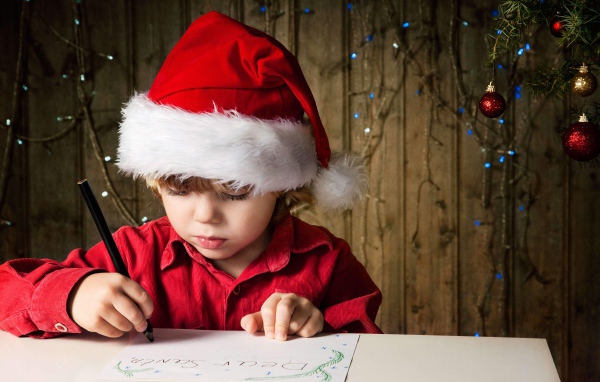 Маленький мальчик пишет письмо Деду Морозу 