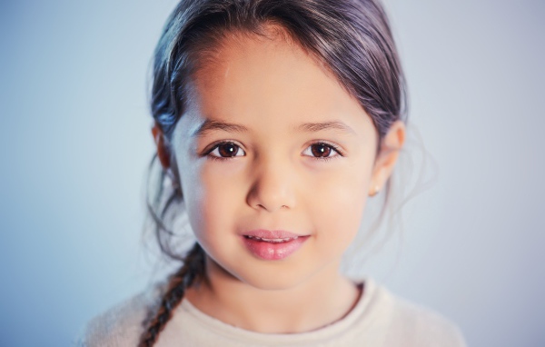 Маленькая кареглазая девочка на сером фоне