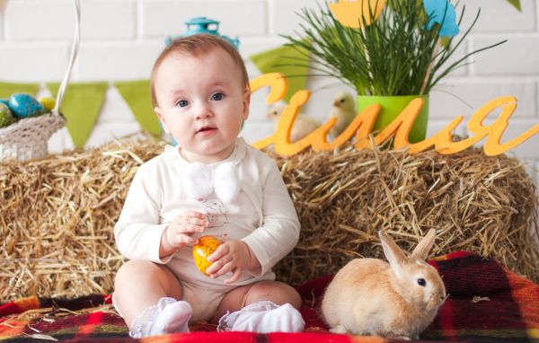Маленький ребенок с крашеным яйцом и декоративным кроликом