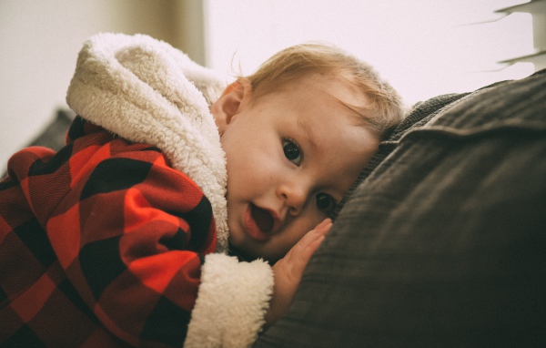 Маленький забавный малыш лежит на диване