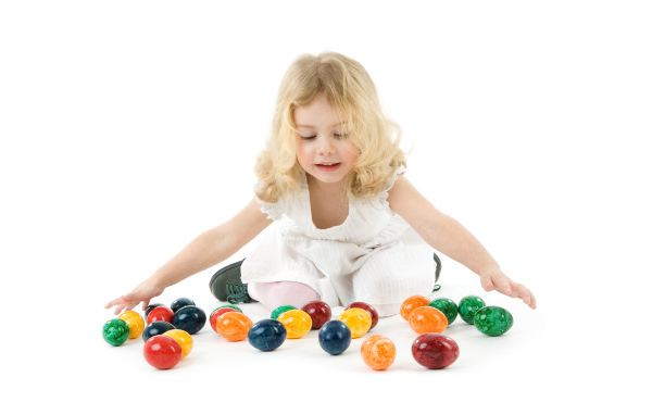 Маленькая девочка блондинка с крашеными яйцами на белом фоне