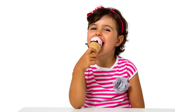 Маленькая девочка ест мороженое за столом на белом фоне