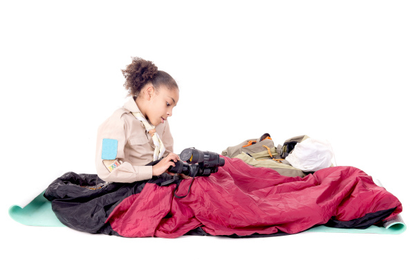 Маленькая девочка в спальном мешке с биноклем