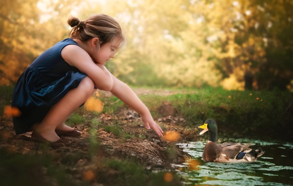 Маленькая девочка играет с уточкой в воде