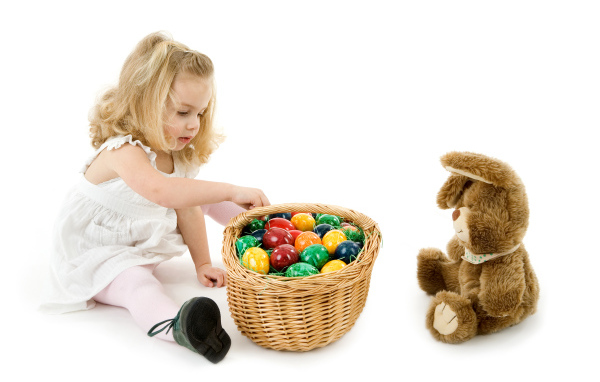 Маленькая девочка с корзиной крашеных яиц и игрушечным кроликом