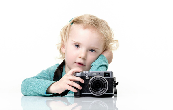 Маленькая девочка с фотоаппаратом на белом фоне