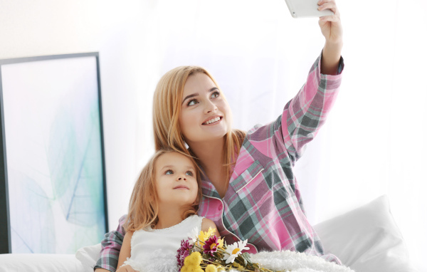 Маленькая девочка с мамой делают фото на смартфон