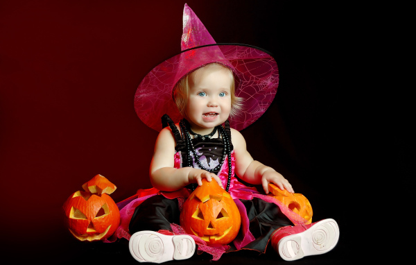 Маленькая девочка с тыквой в костюме на праздник Хэллоуин 