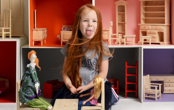 Маленькая длинноволосая девочка показывает язык