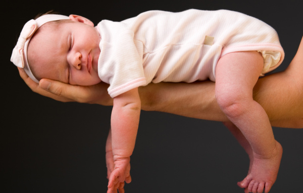 Спящий ребенок на руке у папы на сером фоне