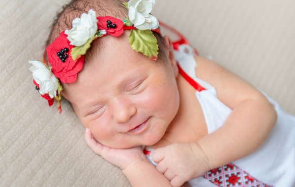 Улыбающаяся спящая девочка с венком на голове