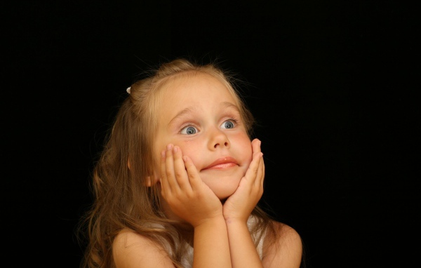 Удивленная маленькая девочка на черном фоне