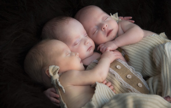 Три маленьких грудных ребенка спят обнявшись 