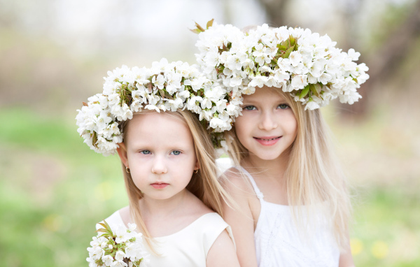 Две милые маленькие девочки с венками из цветов вишни на голове