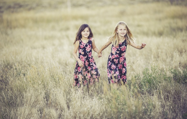 Две маленькие девочки бегут по траве