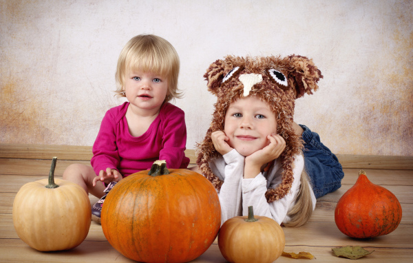 Два маленьких ребенка с тыквами в комнате